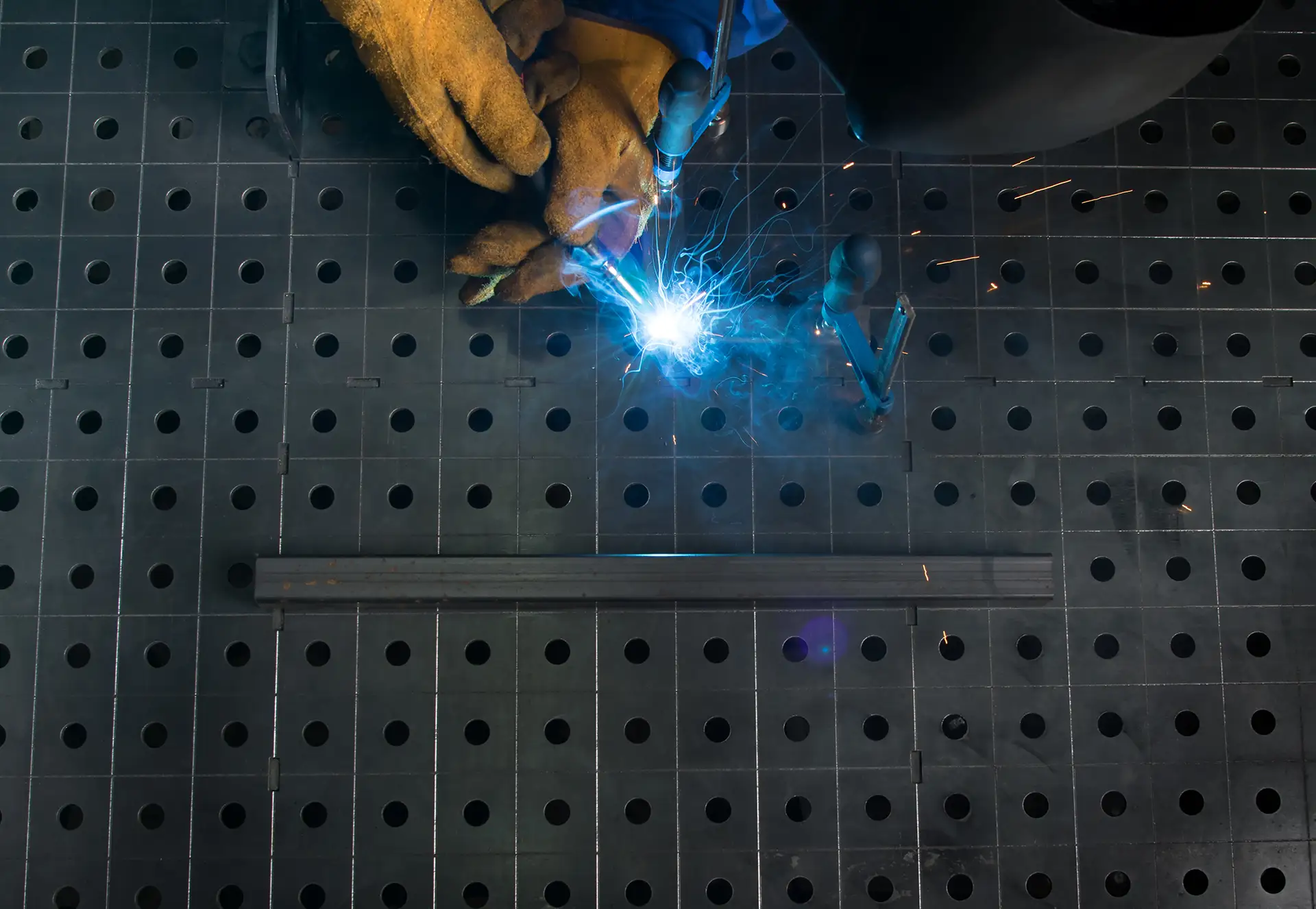 blue light from the welding machine, the process of fastening metal parts, on a black metal table